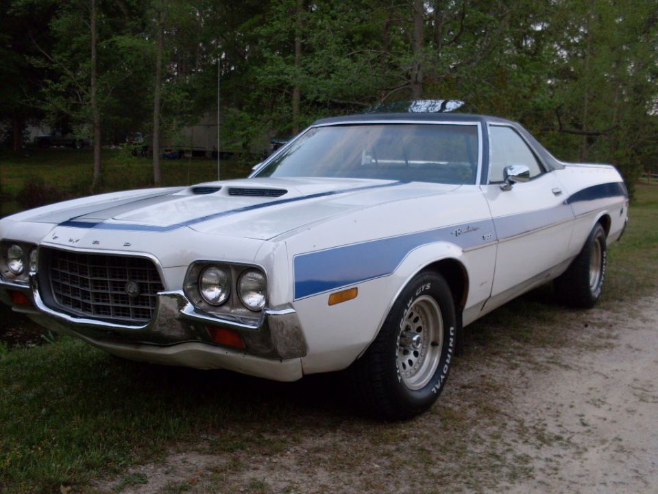 White Ford Ranchero with blue stripes, front 3/4 view on dirt driveway