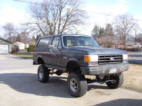 1988 Ford Bronco - This lifted 1988 Ford Bronco is shown from a 3/4 front angle, highlighting its off-road modifications.