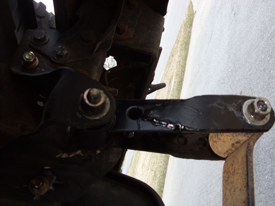 Black painted suspension arm with visible welds and a bolt