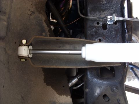 1988 Ford Bronco - Underside view of a vehicle's suspension system, focusing on a shock absorber and related mechanical parts.