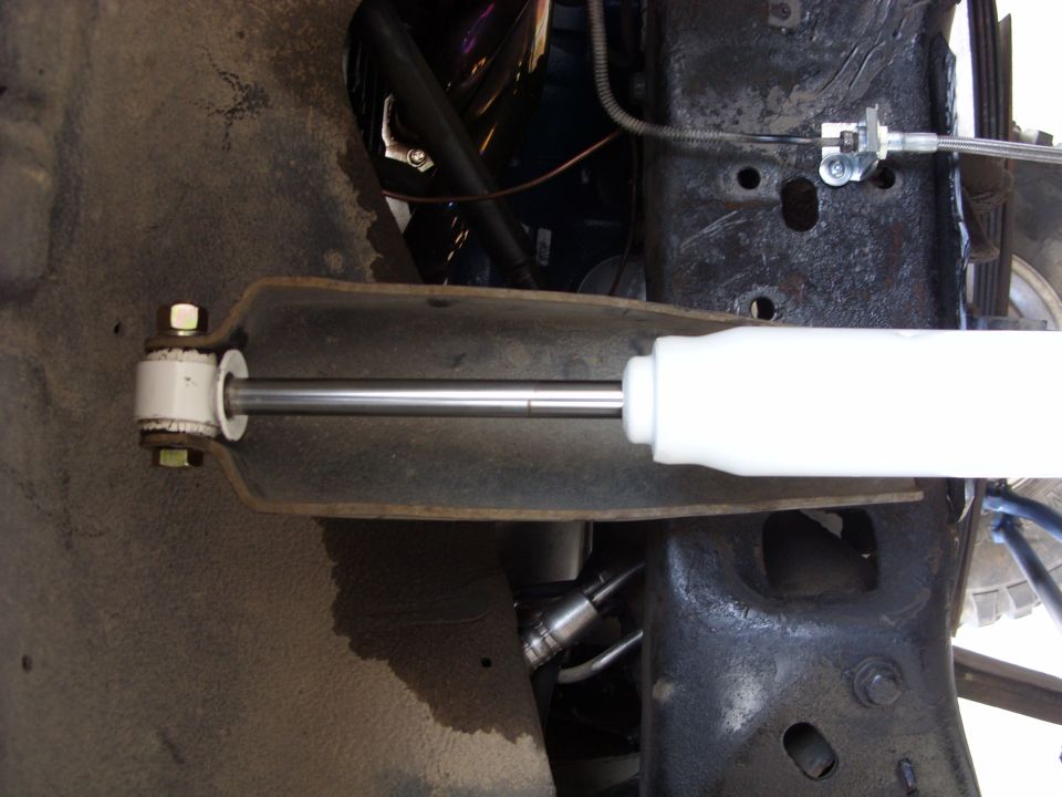 Close-up of a white shock absorber and suspension linkage on a vehicle's undercarriage