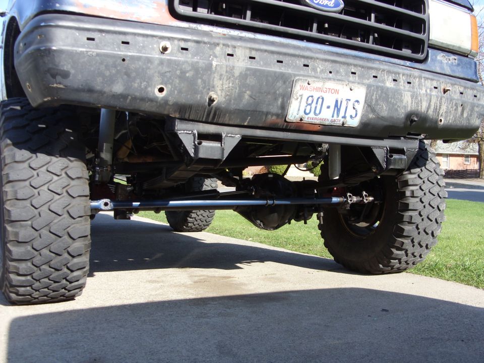 Under-front view of a lifted Ford 4x4 showing solid front axle and crossover steering linkage