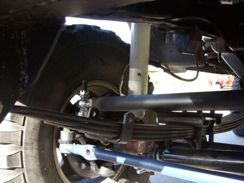 Underbody view of lifted 4x4 leaf-spring front suspension, sway bar and tie rod