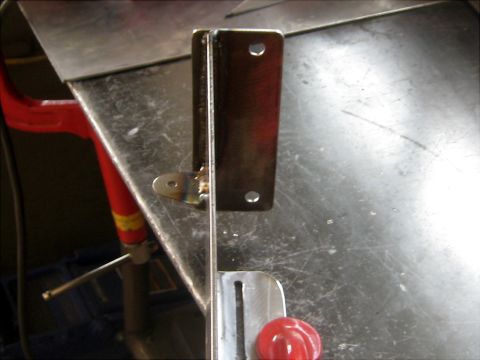 1996 Ford Bronco - Close-up of a metal bracket with a small hinge, likely a component for a larger assembly.