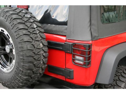 2008 Jeep Wrangler - Rear view of a red Jeep Wrangler, showing the tail light guards and a spare tire mounted on the back.