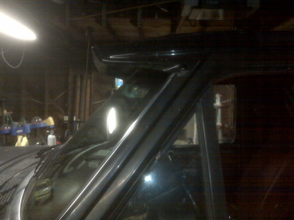 Black SUV parked inside a garage, showing the roofline and windshield area