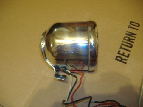 1987 Ford Crown Victoria LTD - Chrome headlight assembly with wiring, resting on a cardboard surface with text.