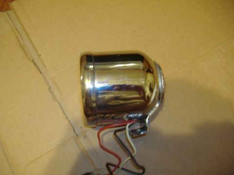 1987 Ford Crown Victoria LTD - A single chrome headlight with exposed wiring sits on a cardboard surface. The Supermotors logo is visible in the lower right corner.