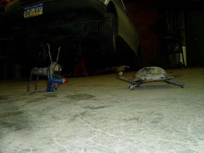 Metal sculptures of a turtle and an insect with a toy gun in a garage.