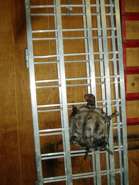 2000 Ford E350 - A differential cover is bolted to a silver metal ramp. The ramp is leaning against a wooden wall.