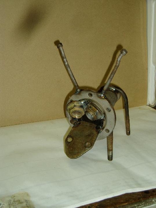 Metal sculpture made from various automotive parts, resembling a dog's head with two antennae