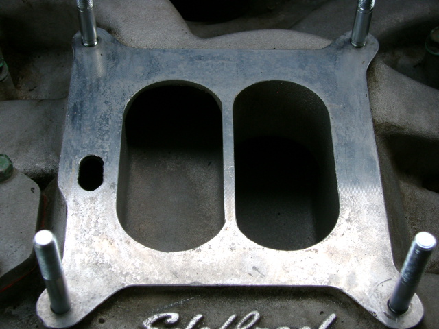 Aluminum open carburetor spacer with two oval bores mounted on an Edelbrock intake manifold