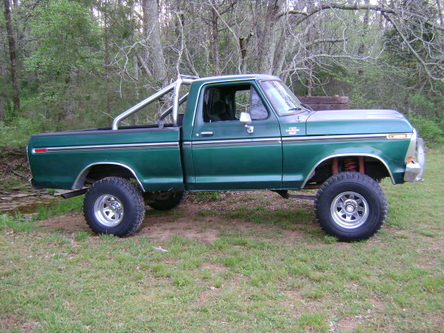 1979 Ford F-150 pickup truck, green, lifted, with roll bar in bed, parked on grass