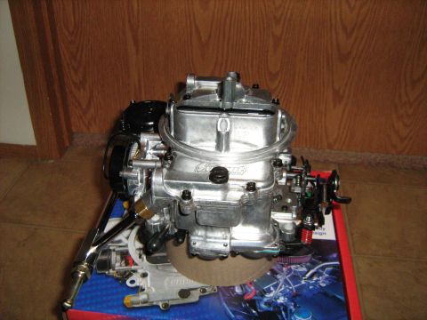 1988 Mercury Grand Marquis - A close-up view of a shiny Holley carburetor, resting on a box with a Supermotors.net logo.