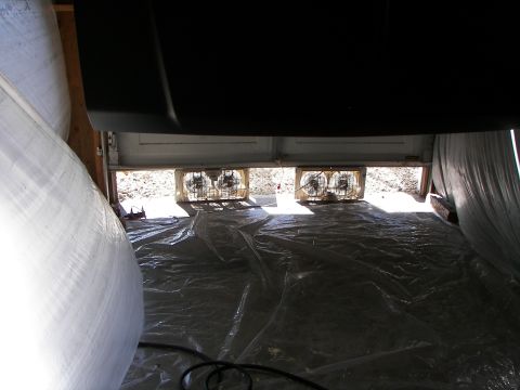 1987 Ford Bronco - Two fans are positioned in a garage doorway, set up on a plastic-covered floor.