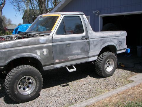 1987 Ford Bronco - This SUV is undergoing bodywork and is shown in primer with aftermarket wheels and step bars.