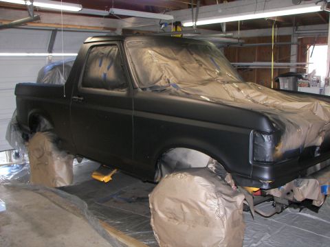 1987 Ford Bronco - A 1987 Ford Bronco is covered in masking paper and plastic, ready for a new coat of paint in a garage setting.