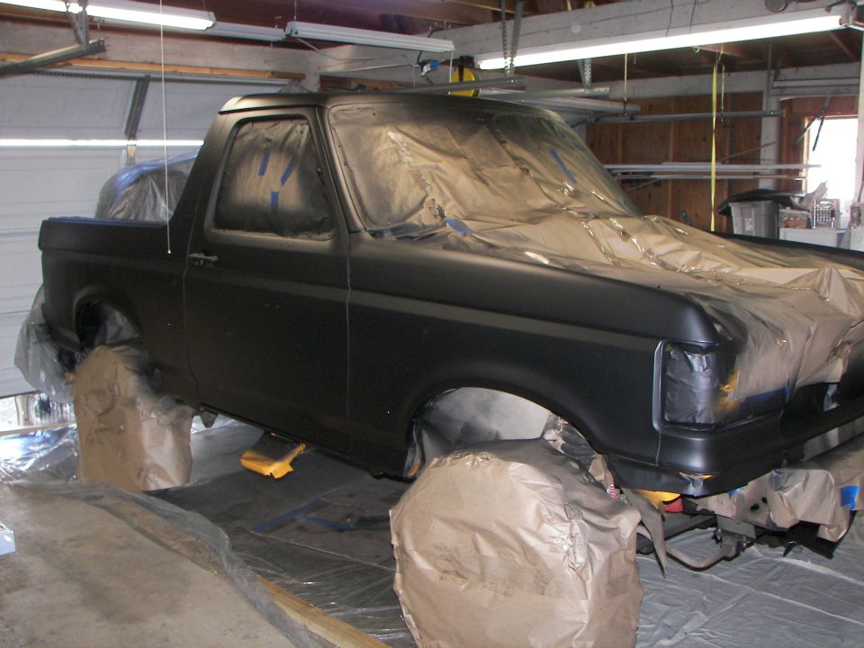 Black 1987 Ford Bronco being prepped for paint, masked and covered