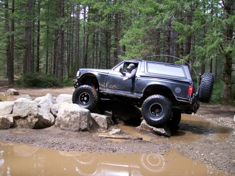 1991 Ford Bronco - This 1991 Ford Bronco is tackling a challenging off-road trail with large rocks and mud.