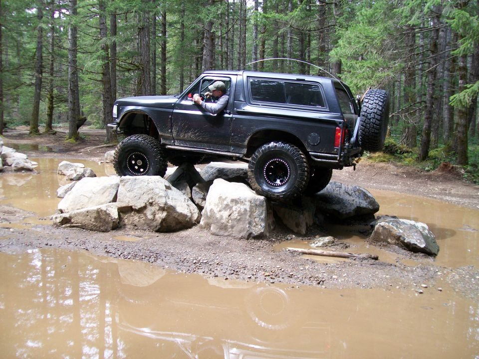 1991 Ford Bronco navigating a rocky obstacle course in a forest