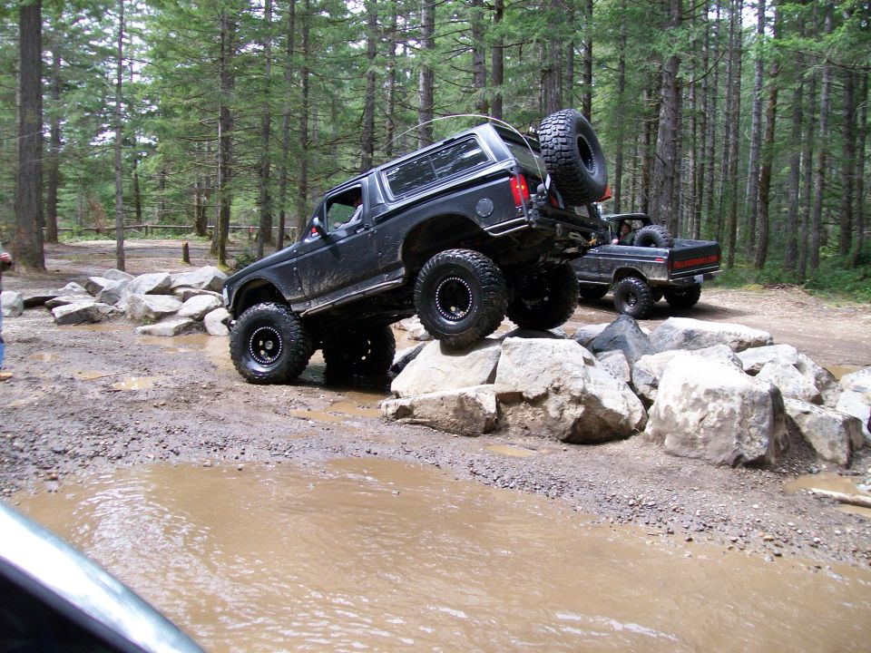 Black 1991 Ford Bronco navigating rocky terrain with a second vehicle behind