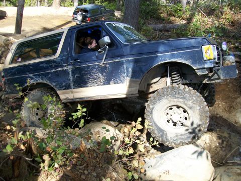 1991 Ford Bronco - A Ford Bronco tackles a challenging off-road course, with another vehicle visible in the background.