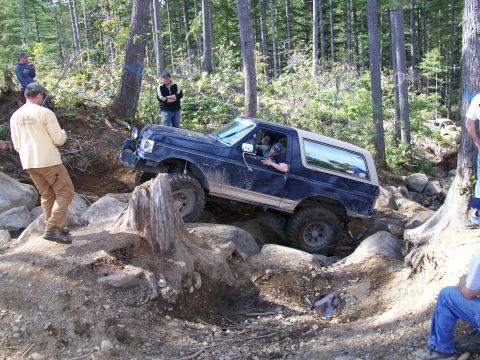1991 Ford Bronco - Off-roading event shows a 1991 Ford Bronco tackling a challenging rocky obstacle.