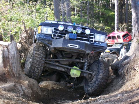 1991 Ford Bronco - A modified Ford Bronco navigates a challenging off-road course with other vehicles in the background.