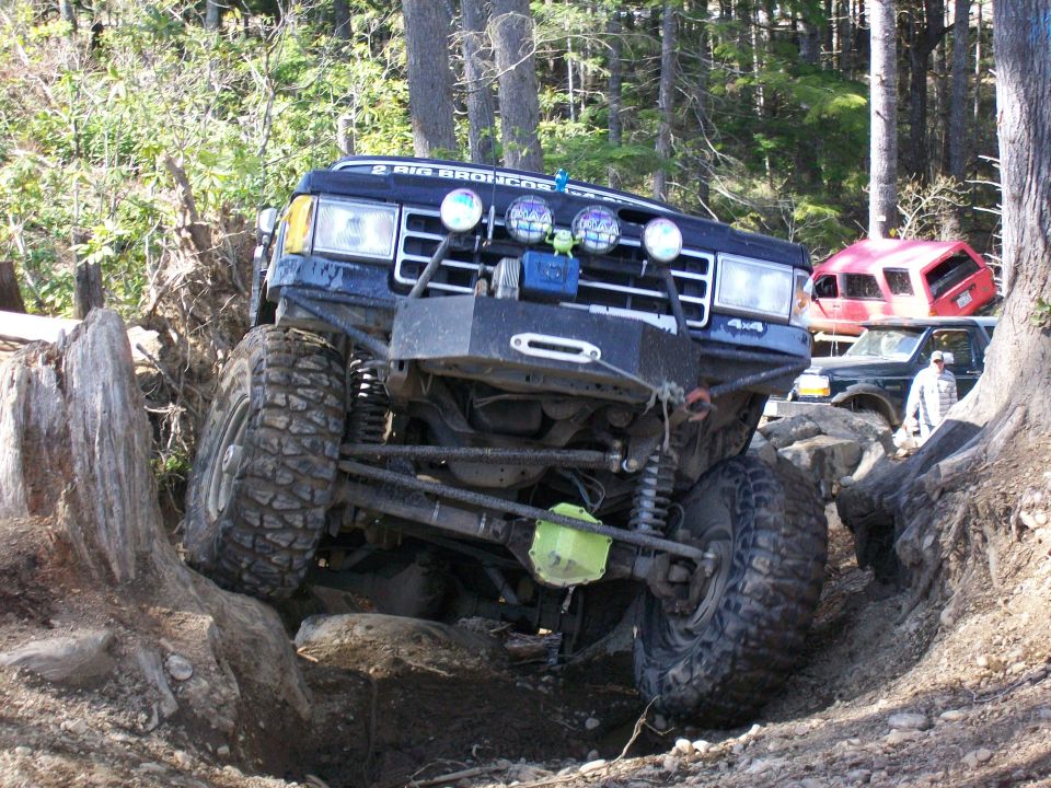 Blue Ford Bronco off-roading, front bumper and winch visible, large tires, on a rocky trail