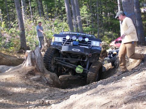 1991 Ford Bronco - Modified 1991 Ford Bronco tackling an off-road obstacle with other vehicles nearby.