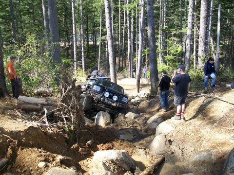 1991 Ford Bronco - Off-roading event with multiple vehicles tackling a challenging rocky course in a wooded area.