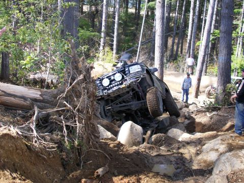 1991 Ford Bronco - An off-road vehicle navigates a challenging rocky terrain with a fallen tree nearby.