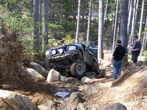 1991 Ford Bronco - A black 1991 Ford Bronco tackles a challenging rocky terrain, demonstrating its off-road capabilities with two spectators observing the act…