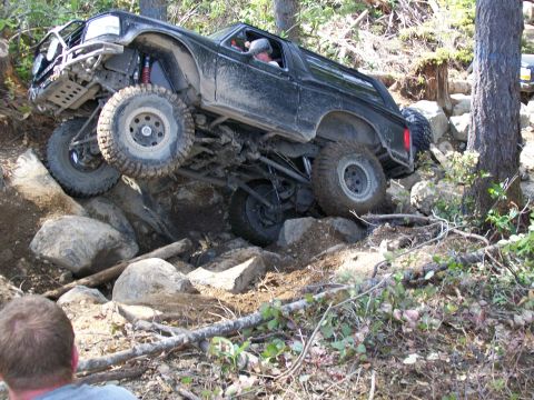 1991 Ford Bronco - A heavily modified SUV tackles a challenging off-road course with steep inclines and large rocks.
