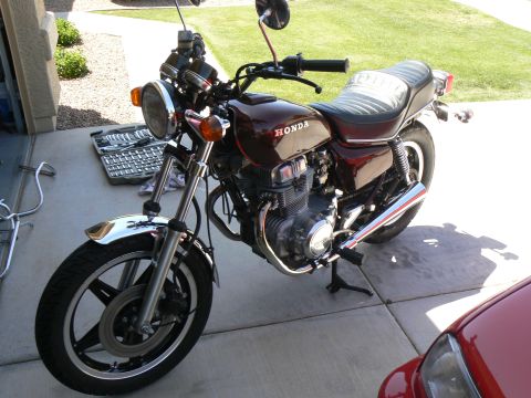 1978 Ford Bronco - Maroon Honda motorcycle with chrome accents and a black seat, parked outdoors.