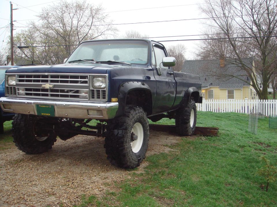 Lifted dark blue Chevrolet square-body pickup on large mud tires
