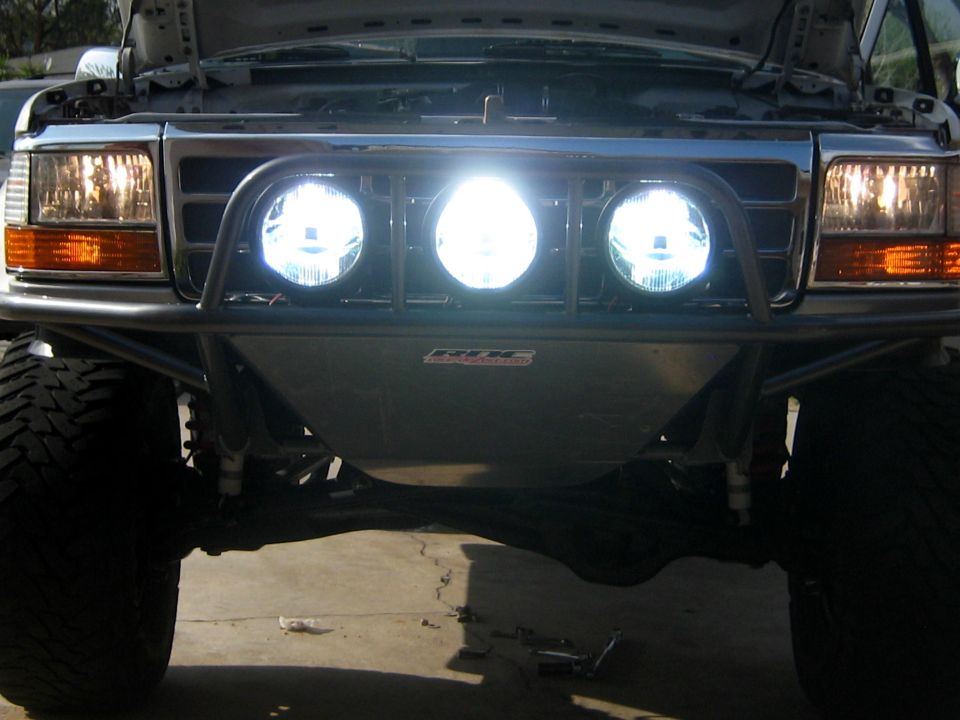Front of a Ford truck with a custom bumper and three large spotlights. The grille and headlights are visible