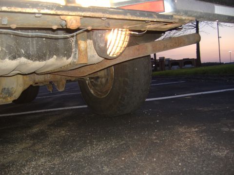1988 Ford Bronco - Close-up of the undercarriage of a vehicle, revealing the rear tire and fuel tank. The Supermotors watermark is present.