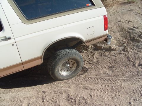 1995 Ford Bronco - This 1992 Ford Bronco is stuck in the dirt, showing its rear quarter panel and wheel.