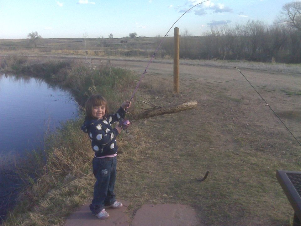 Young girl fishing with a pink fishing rod.