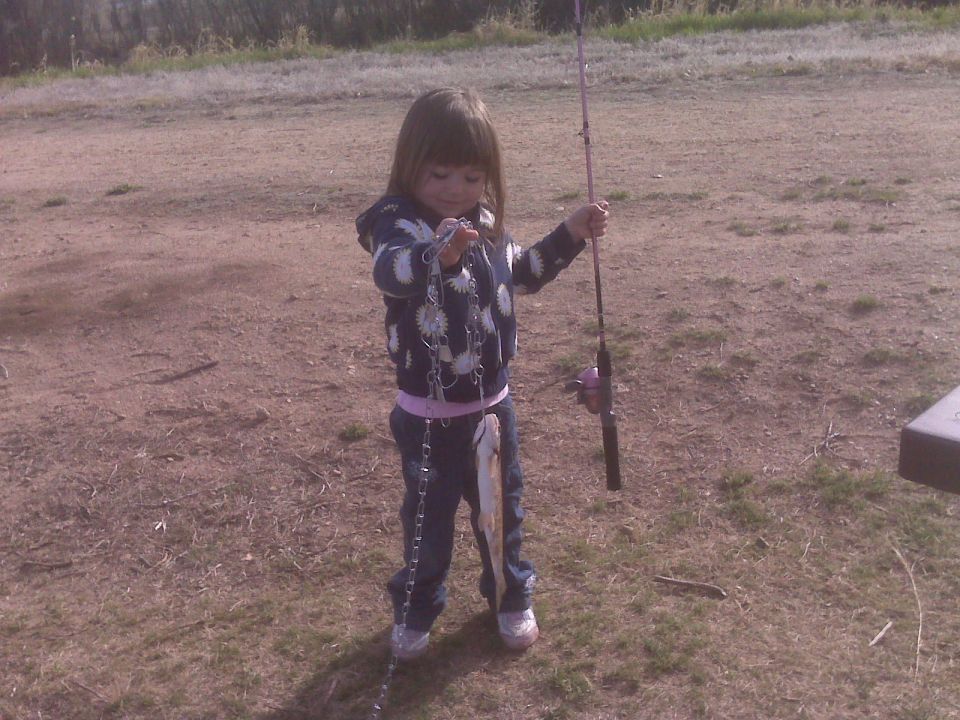 A young girl holding a fishing pole and a fish.