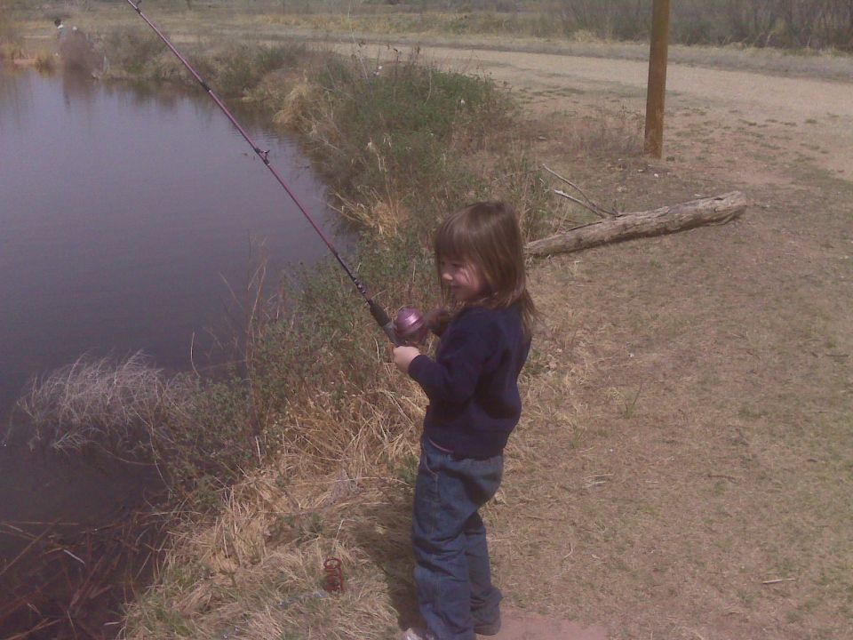 Young girl fishing by a lake.