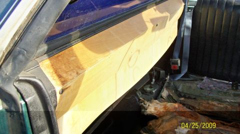 1972 Ford Ranchero - The interior of a vehicle shows a custom wooden panel installed along the door frame and a black seat with a seatbelt. The floor of the veh…