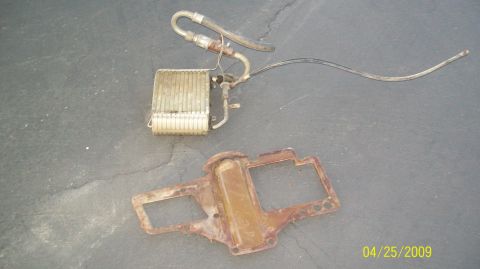 1972 Ford Ranchero - A vintage car heater core with hoses is displayed next to a rusted Chevrolet bowtie emblem on a concrete surface. The scene is dated 04/25/…