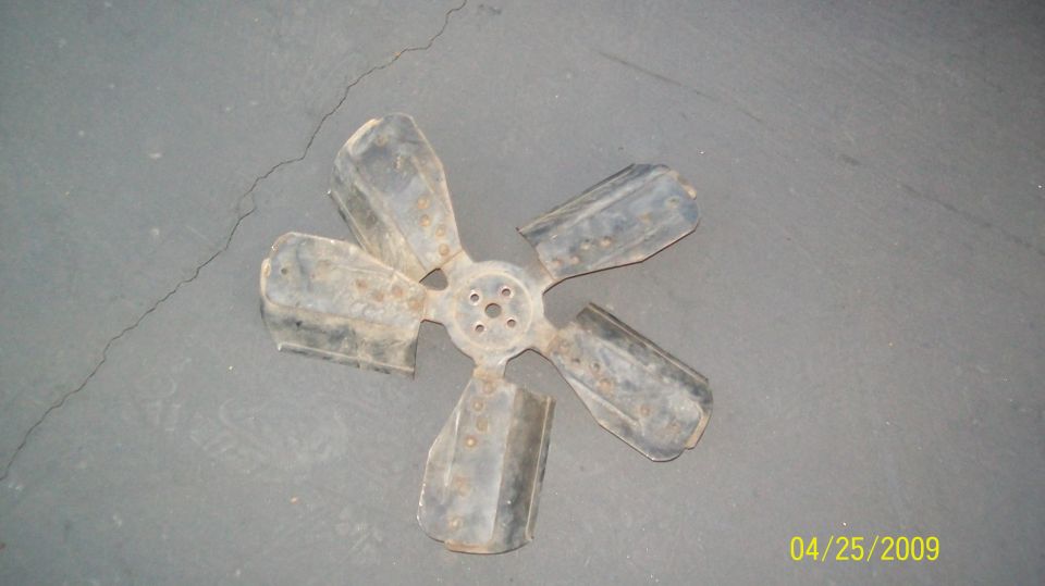 Metal fan with five blades on a cracked concrete surface.
