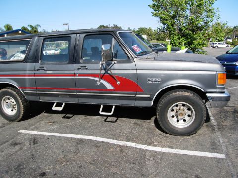 1986 Ford Bronco - This Ford F-Series SUV, likely a 1987 model, features a two-tone paint scheme with a red stripe.