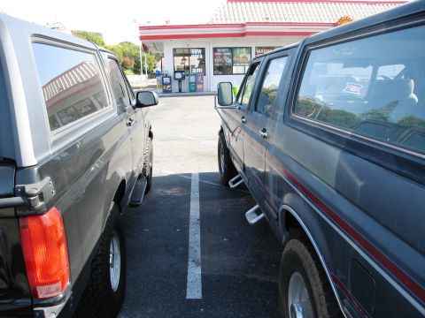 1986 Ford Bronco - Two Ford Broncos are parked next to each other in a parking lot.
