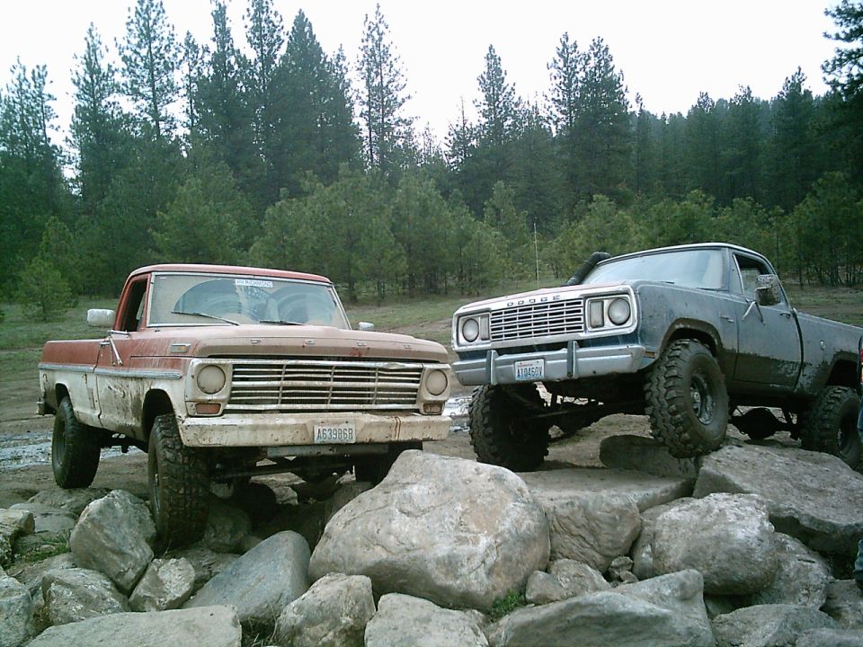 Front view of a blue Dodge pickup truck with large tires, positioned on rocks