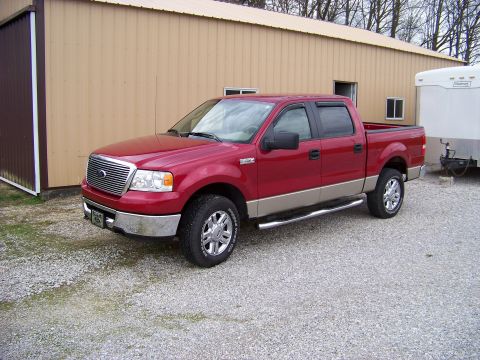 2008 Ford F-150 - A red pickup truck with a tan lower body trim is parked on a gravel lot next to a building.