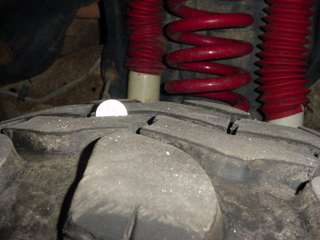 Coin on a large tire tread, red coil springs and red shock boots visible